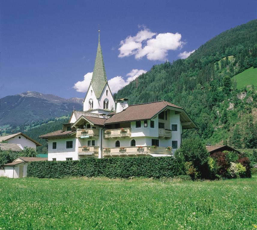 ein großes weißes Gebäude mit einem Kirchturm auf einem Feld in der Unterkunft Appartements St. Leonhard in Aschau