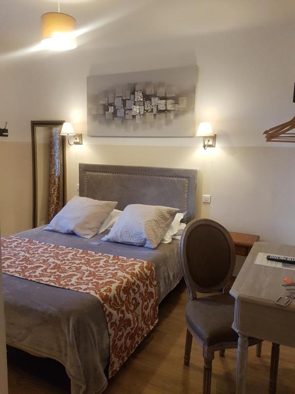 een slaapkamer met een bed, een stoel en een tafel bij Hostellerie de la Crémaillère in Carnoux