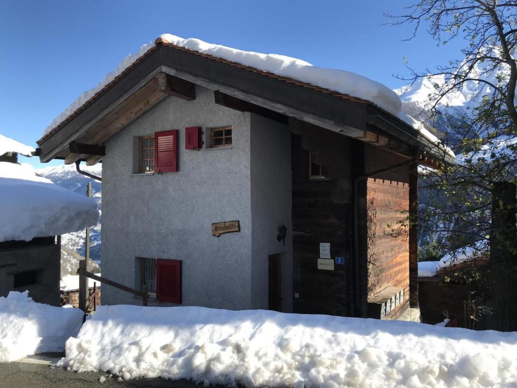 a small house with red shutters in the snow at Apartment Stubulti by Interhome in Mörel