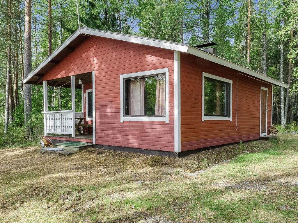 a small red house with a porch in the woods at Holiday Home Haapalehto by Interhome in Nurmes