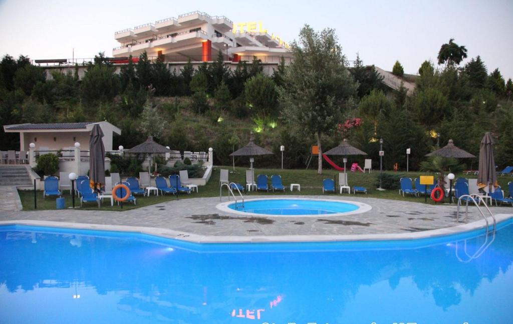 uma piscina com cadeiras e um edifício ao fundo em Acropol Hotel em Serres