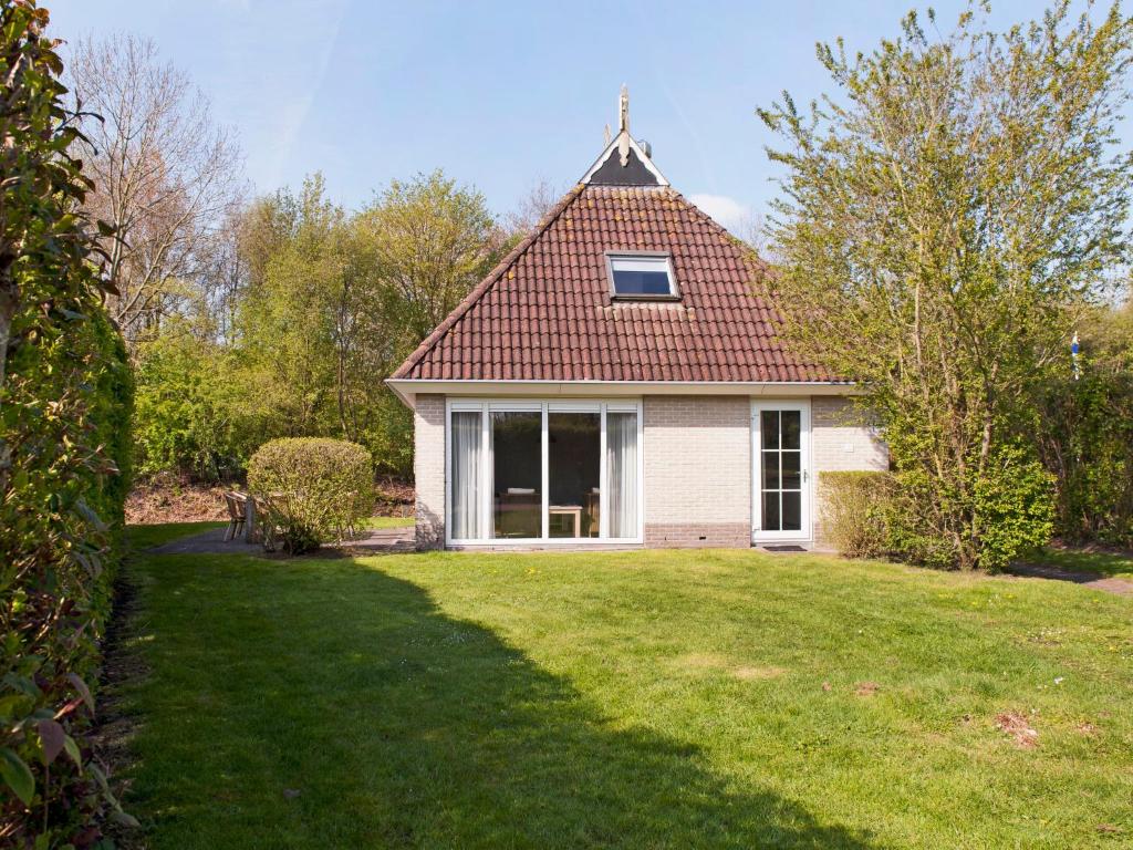 a small house with a pitched roof on a yard at Holiday Home Bungalowpark It Wiid by Interhome in Eernewoude