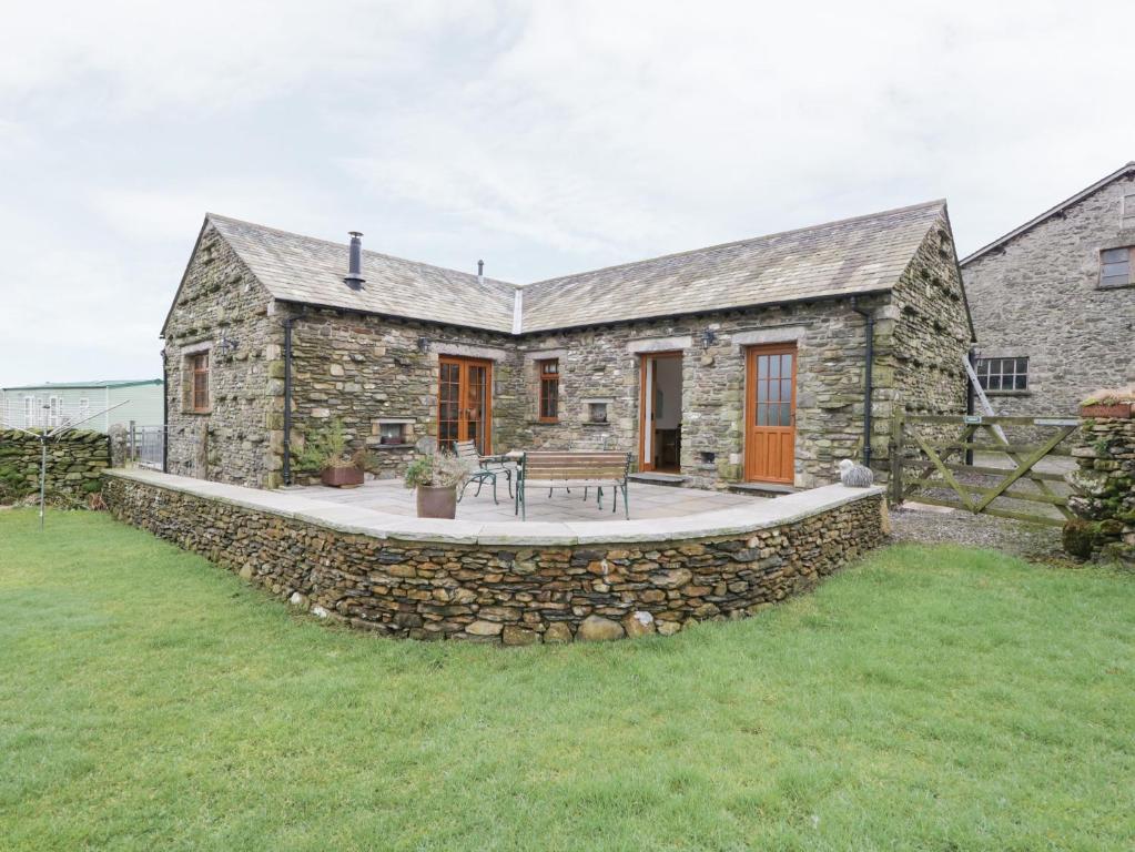 a stone house with a patio and a stone wall at Little Crake Howe in Grayrigg