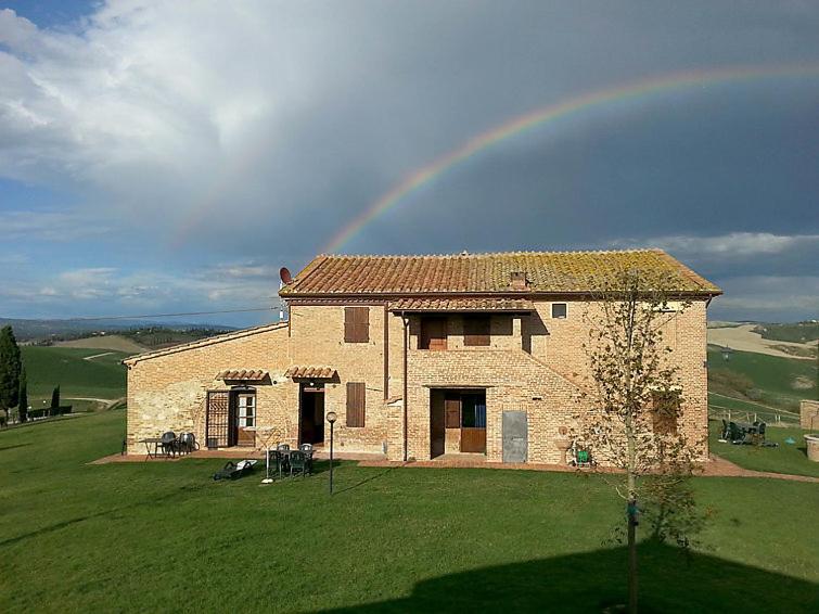 um arco-íris sobre uma casa com um campo verde em Staffolino em Siena