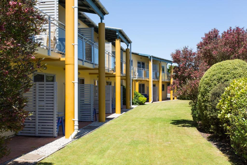 uma fila de casas com colunas amarelas e relva em Greens Motel em Nelson