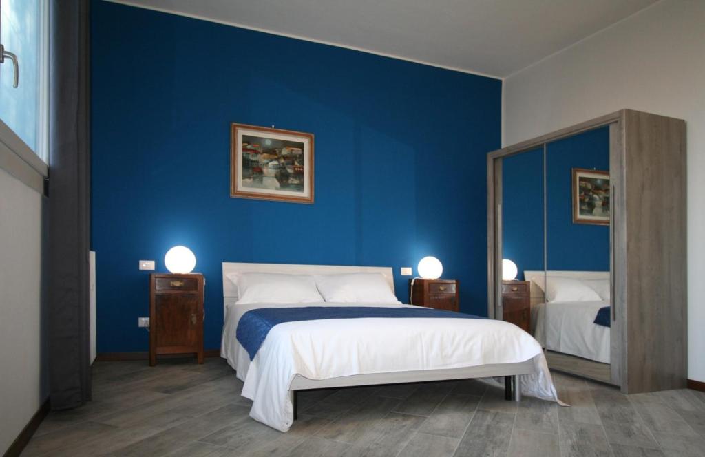 een blauwe slaapkamer met een bed en een spiegel bij SanSiroFiera in Milaan