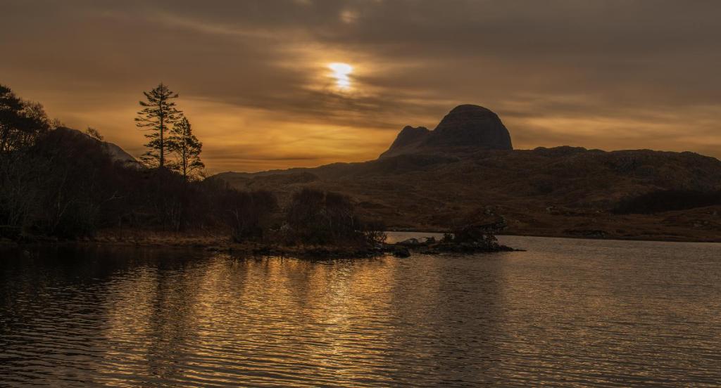 a sunset over a body of water with a mountain at North Coast 500 Pods in Achmelvich
