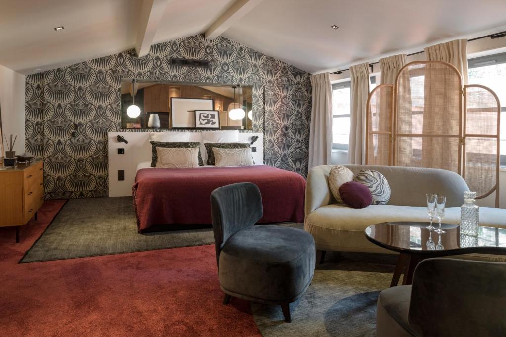 a bedroom with a bed and a couch and a table at MiHotel Tour Rose in Lyon