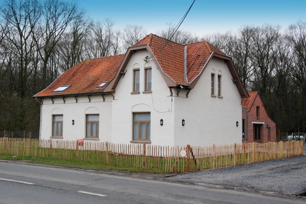 uma casa branca com um telhado vermelho em Jachthuis Au Bois Du Gheer em Le Gheer