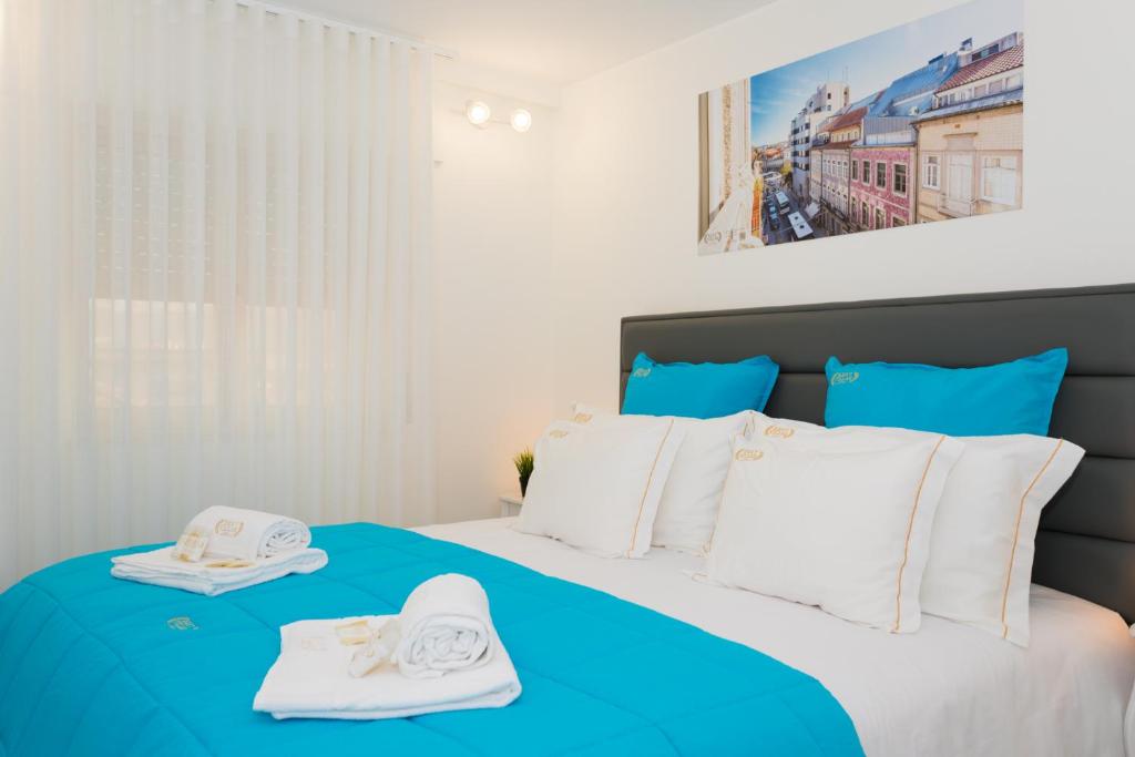 um quarto com uma cama azul e branca com toalhas em BestVillas Foz do Minho em Caminha