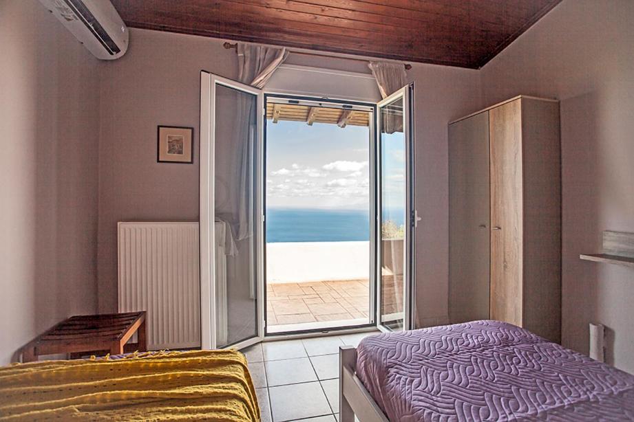 a bedroom with a bed and a view of the ocean at Anatolí Village House in Epáno Kefalás