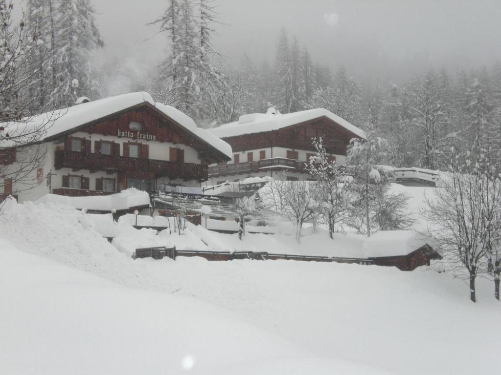 a lodge covered in snow in the woods at Baita Fraina in Cortina dʼAmpezzo