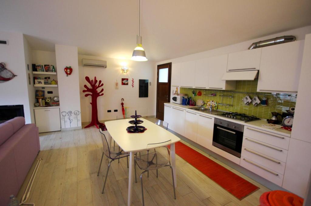 una cucina con armadi bianchi e un tavolo in una stanza di Sa Mirada Apartments a Villasimius