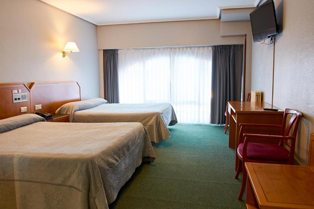 a hotel room with two beds and a television at Hotel San Jorge in Santurce