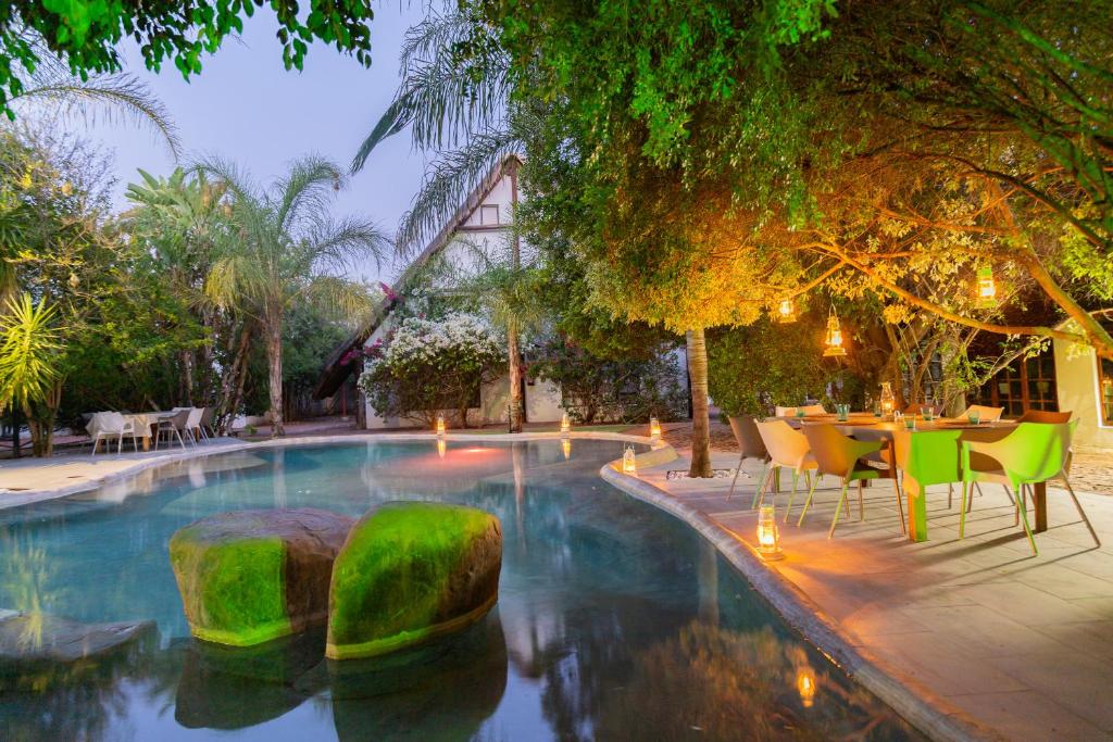 a pool with a table and chairs in a yard at Out of Africa Town Lodge in Otjiwarongo