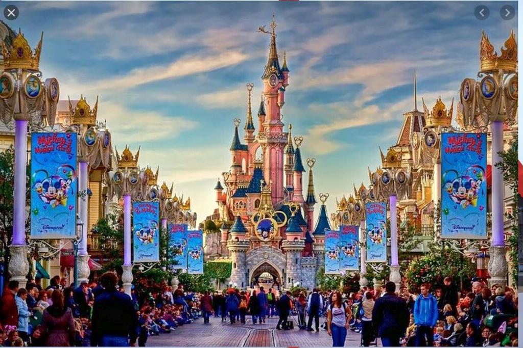 a crowd of people walking in front of a disney castle at 15 min walk to DisneylandParis, 5 min walk to Val d'Europe Mall and train RER A, Monyhome apartment for 4 persons in Chessy