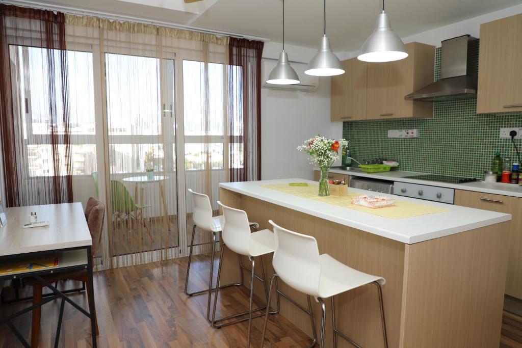 una cocina con una isla con sillas blancas. en Achillion Apartments By 'Flats Nicosia' en Nicosia