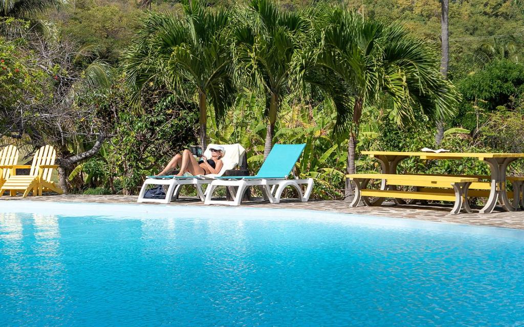 a woman sitting in a chair next to a pool at Firefly Estate Bequia in Crescent Beach