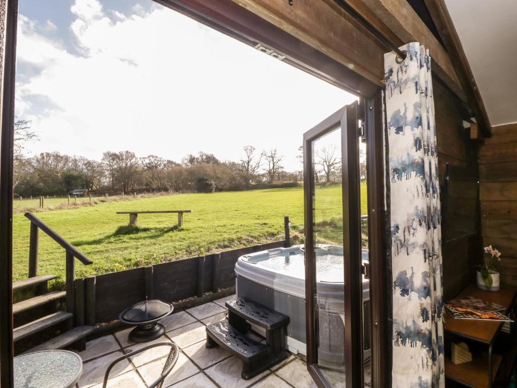 a tub on a patio with a view of a field at Deer lodge at Chapel Lodges in Wimborne Minster