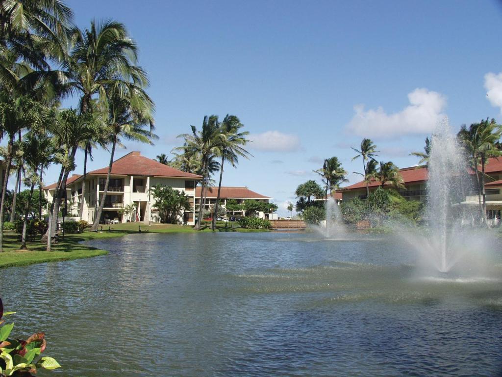 a fountain in the middle of a pond with houses at Kauai Beach Villas in Lihue