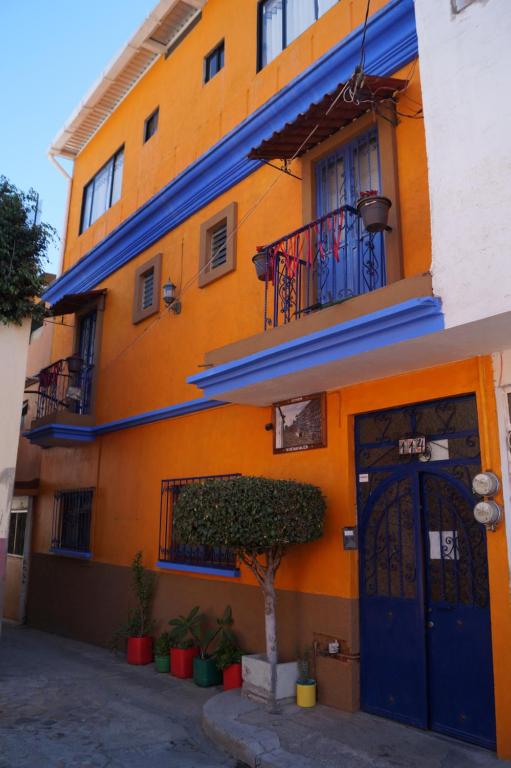 un bâtiment orange avec des portes bleues et un arbre devant lui dans l'établissement Casa Xochimilco, à Oaxaca