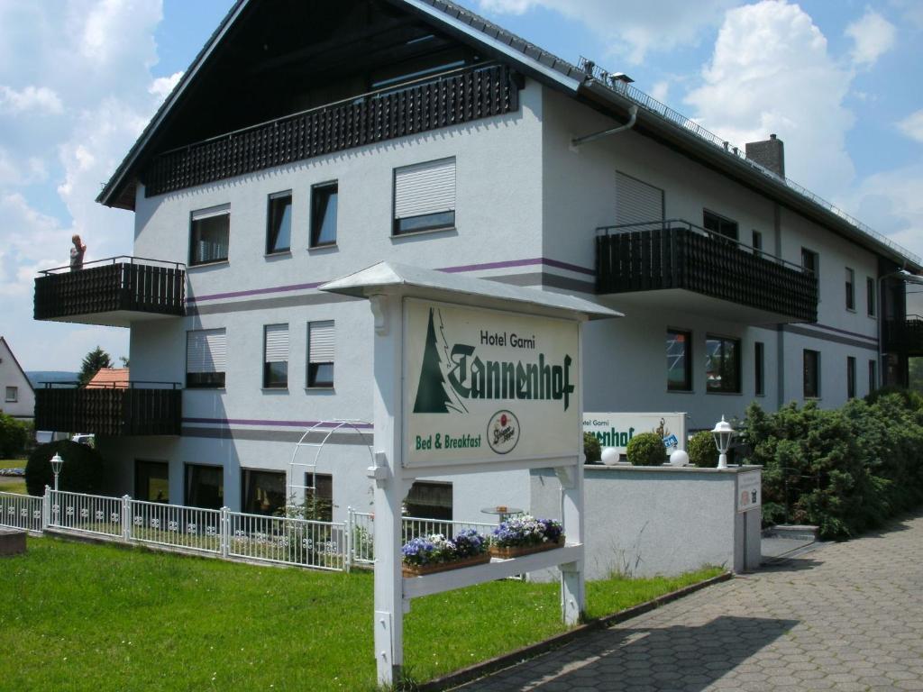 een wit gebouw met een bord ervoor bij Hotel Tannenhof in Erlenbach am Main