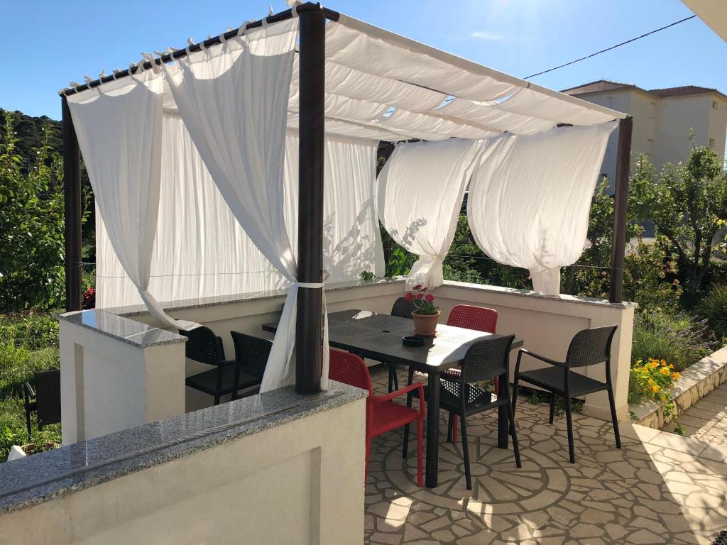 eine Terrasse mit einem Tisch und Stühlen unter einem Baldachin in der Unterkunft Apartments Mikelic in Rab