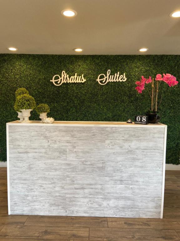 a reception counter with plants on a green wall at Stratus Suites Boutique Hotel in Killeen