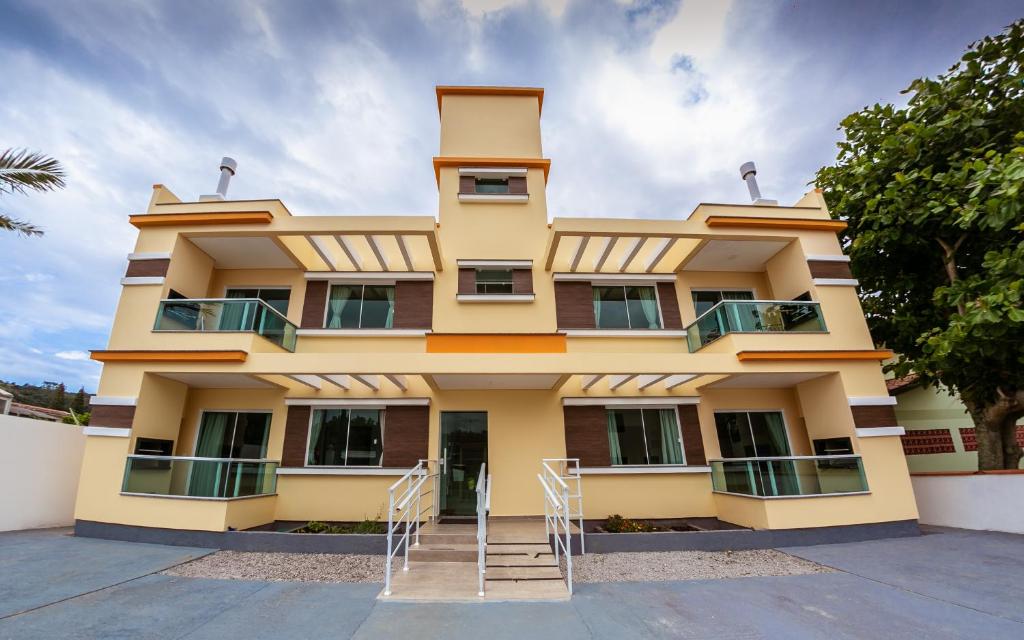 un edificio amarillo con sillas delante en Vila Beach Residence, en Pinheira