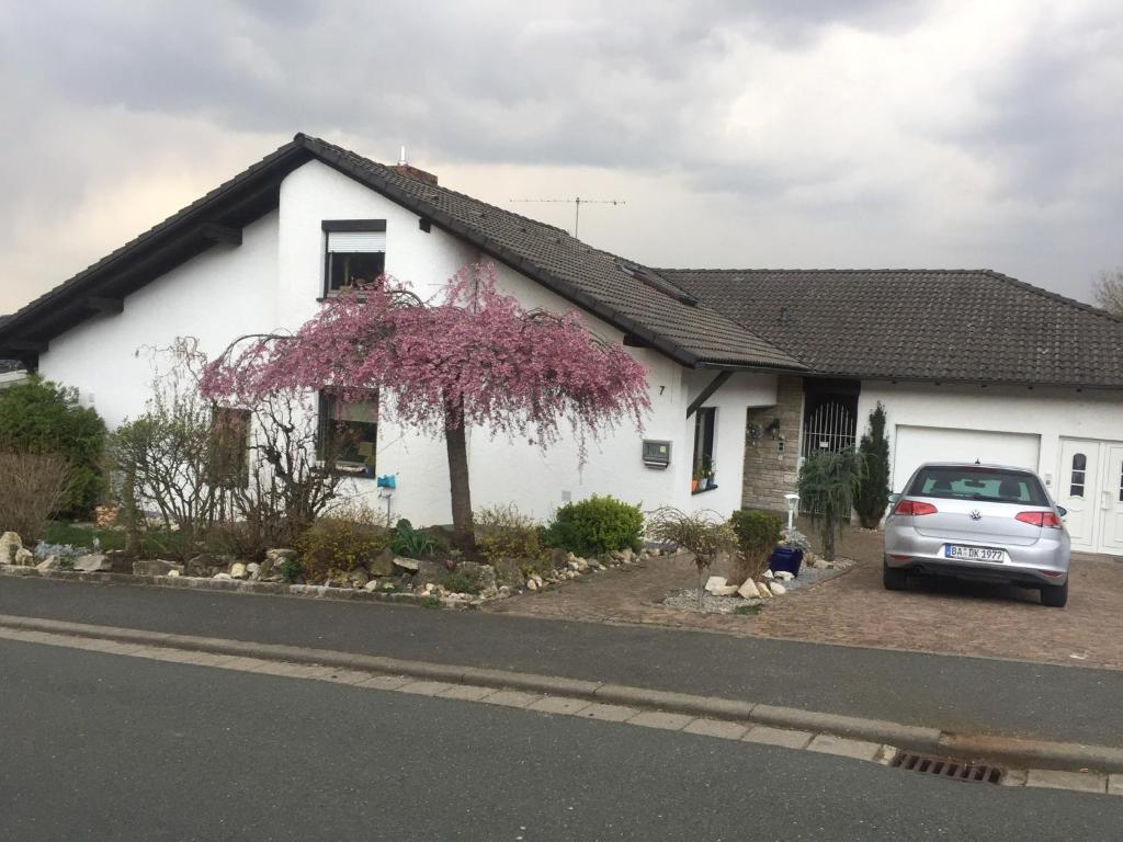 une maison blanche avec une voiture garée devant elle dans l'établissement Ü Villa Resturlaub EG, à Hirschaid
