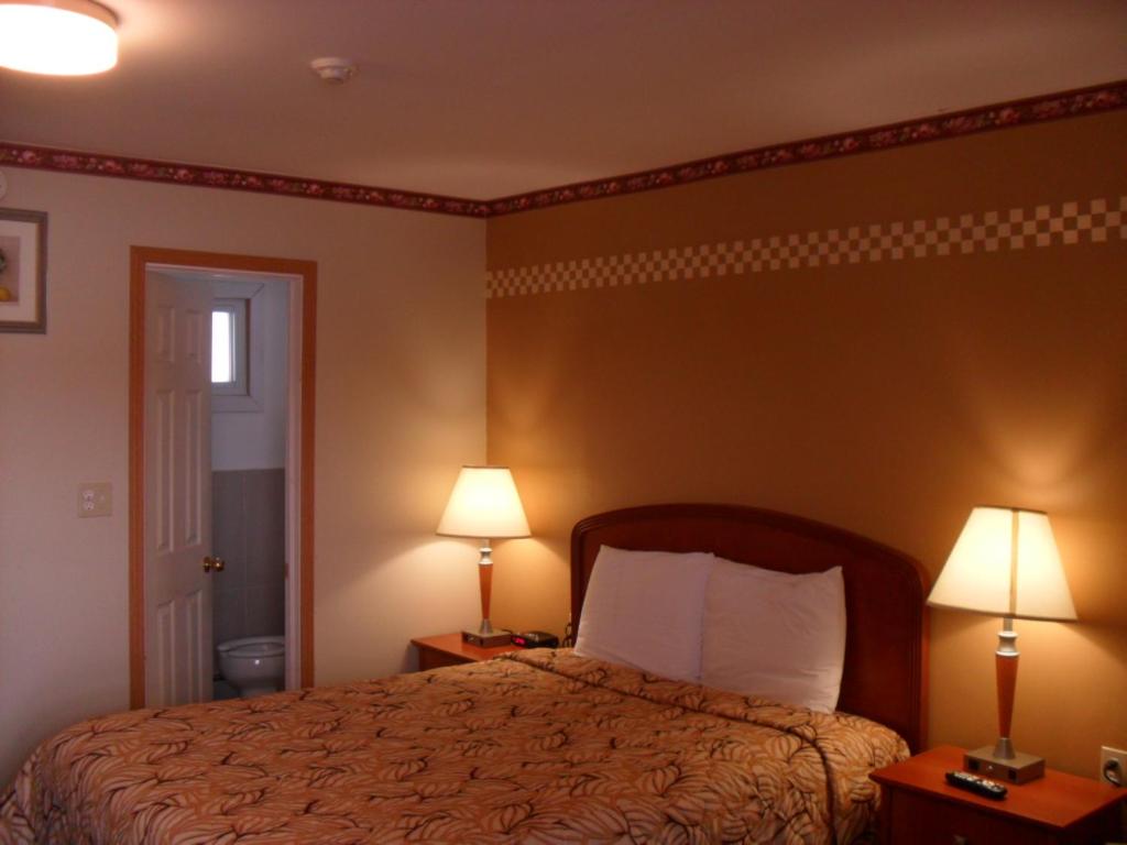 a hotel room with a bed and two lamps at Forest Plaza Motel in Mount Forest
