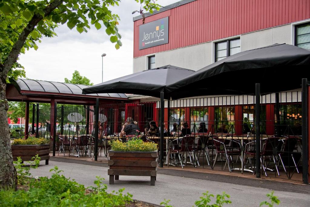 um restaurante com mesas, cadeiras e guarda-sóis em Jennys Hotell och Restaurang em Arvika
