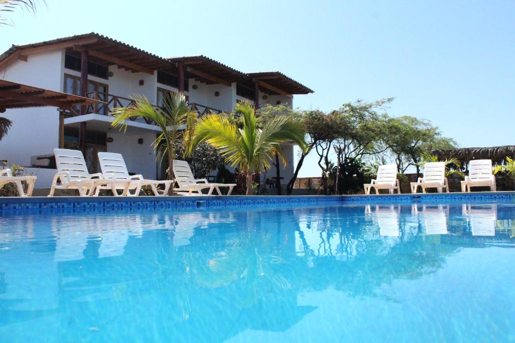 a large swimming pool with chairs and a building at Hotel Casa Vichayo in Vichayito