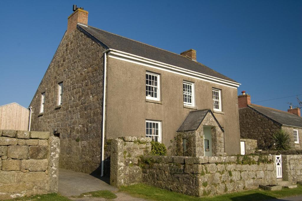 ein altes Steinhaus mit einer Steinmauer in der Unterkunft Tregiffian Farm B&B in Penzance
