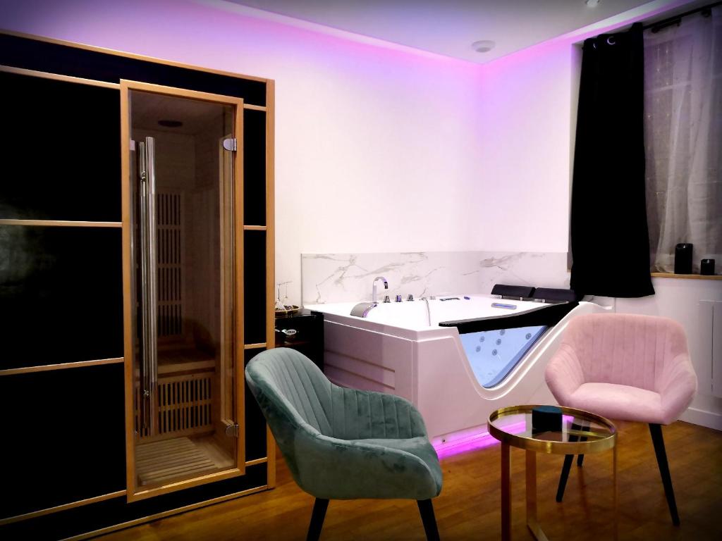 a bathroom with a sink and a chair and a table at Le Vénus - Appartement SPA Privatif Balnéo Sauna in Dijon