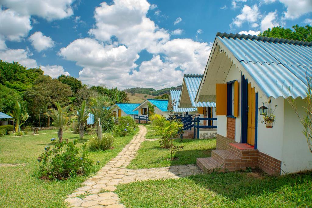 una fila de casas con techos azules en un campo en João e Maria Restaurante e Chalés en Tiradentes