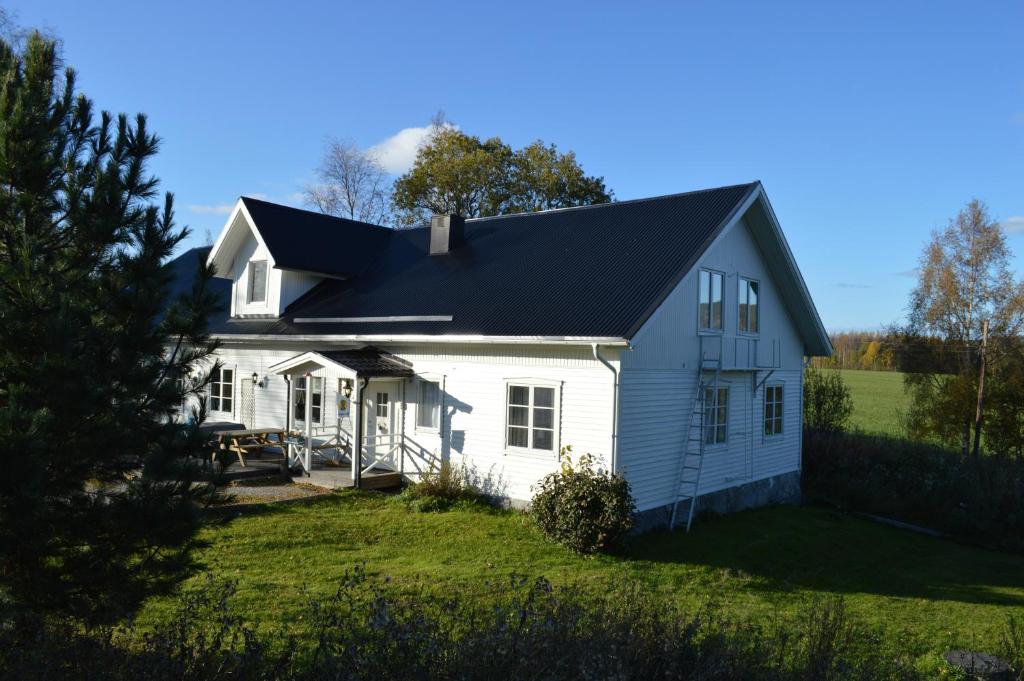 une maison blanche avec un toit noir dans l'établissement Högsnäsgården, à Överhörnäs