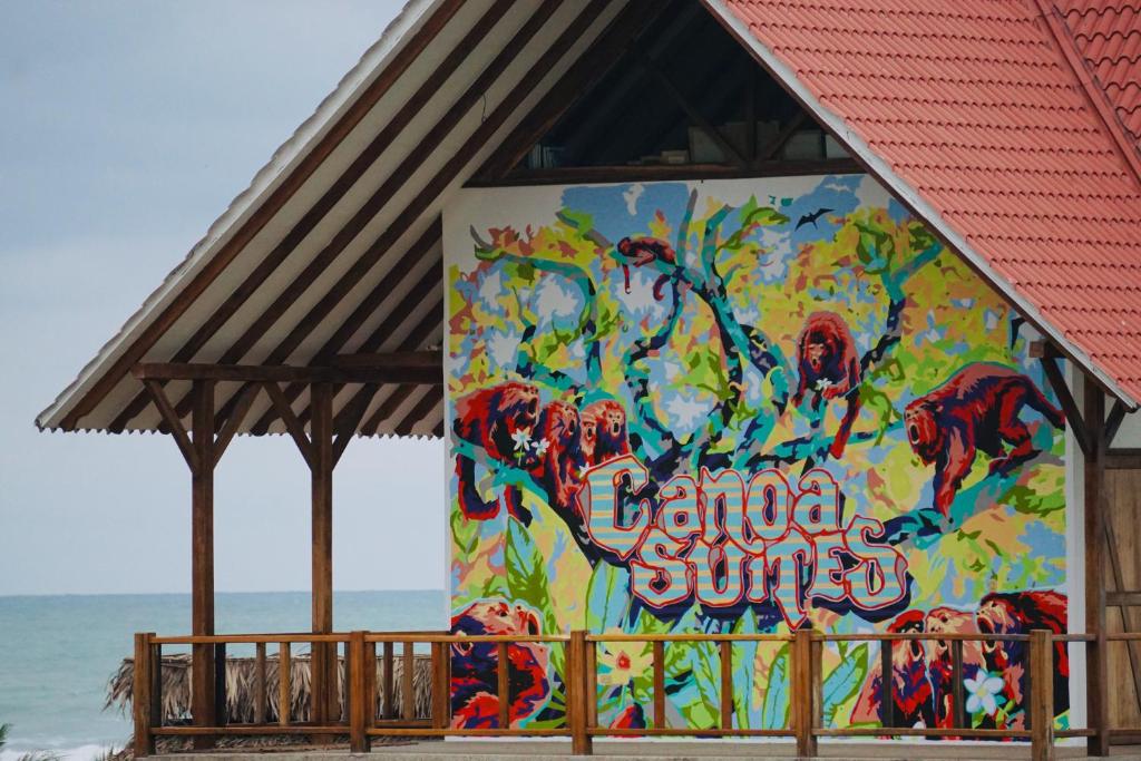 a mural on the side of a building next to the beach at Canoa Suites in Canoa