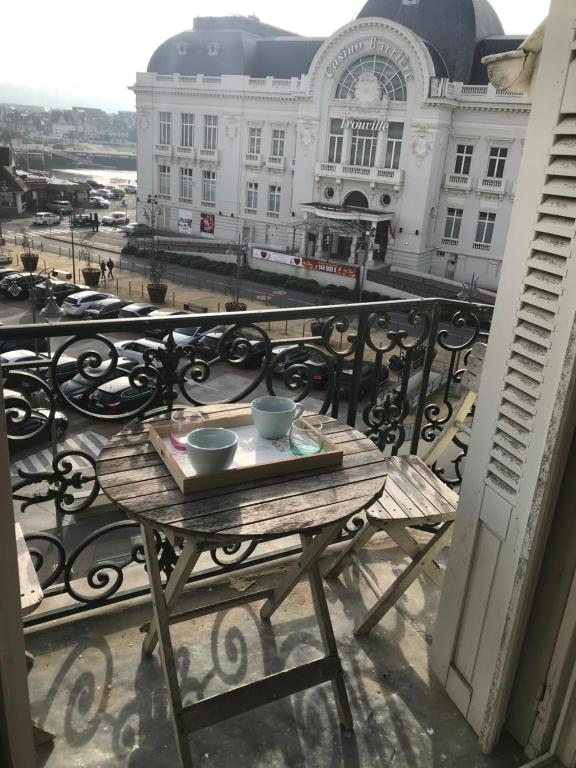 - une table sur un balcon avec vue sur un bâtiment dans l'établissement Le studio de la mer, à Trouville-sur-Mer