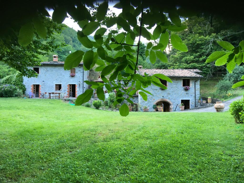 una vieja casa de piedra en un campo de césped verde en Relax totale nel Bosco Lucca, en Ghivizzano