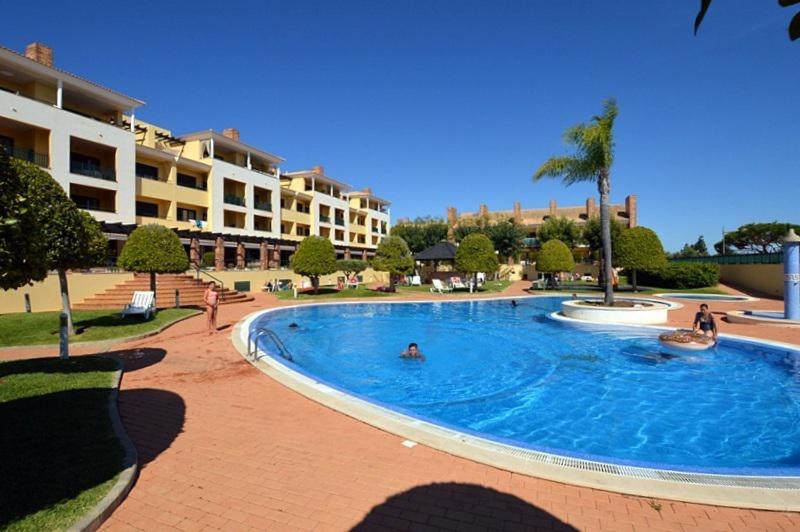 een groot zwembad in een resort met mensen bij CONDOMINIO LOS OLIVOS DEL GOLF in Faro