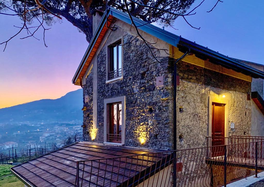 una casa de piedra con terraza al atardecer en Tenuta Novecento Bioagriturismo en Agerola