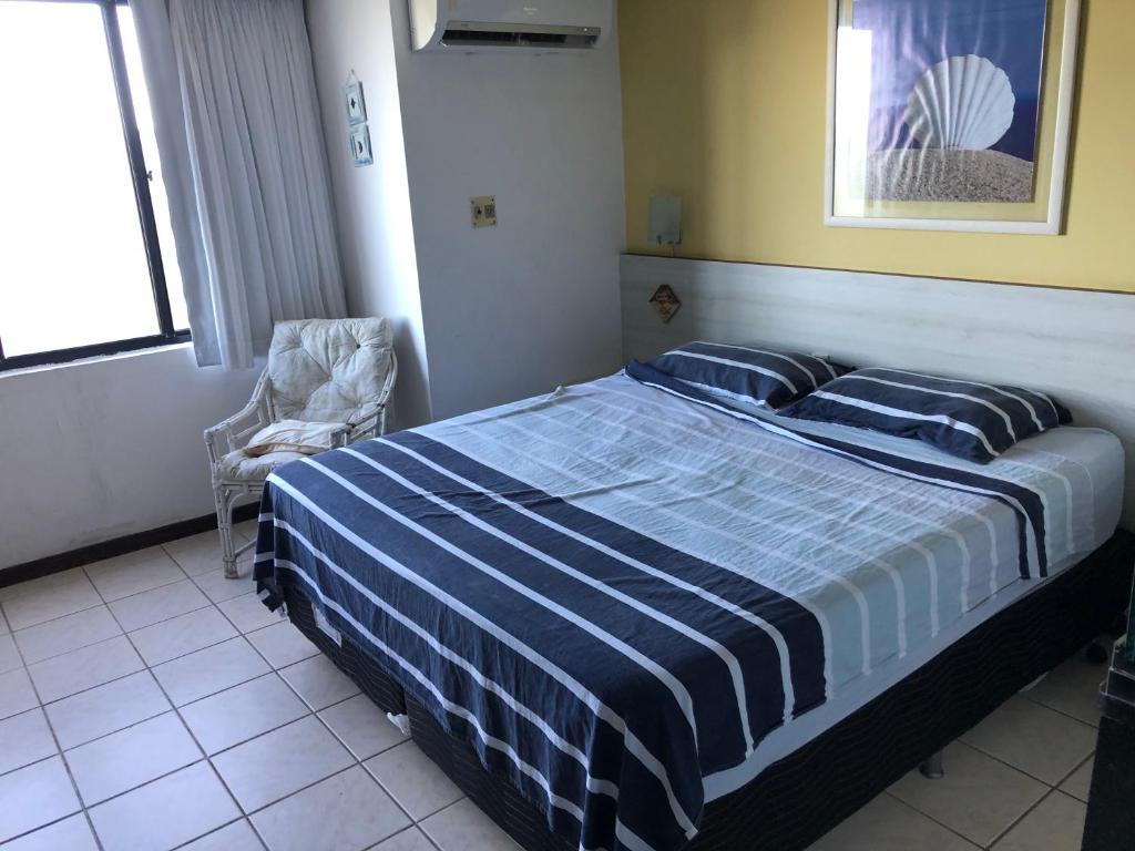 ein Schlafzimmer mit einem Bett mit einer blau-weißen gestreiften Bettdecke in der Unterkunft Atlântico Flat ap 204 em Ponta Negra in Natal