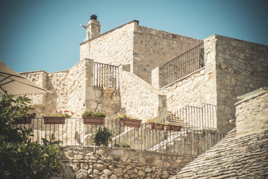TorittoにあるMasseria Storica Pilapalucciの石造りの建物で、階段と鉢植えの植物が飾られています。