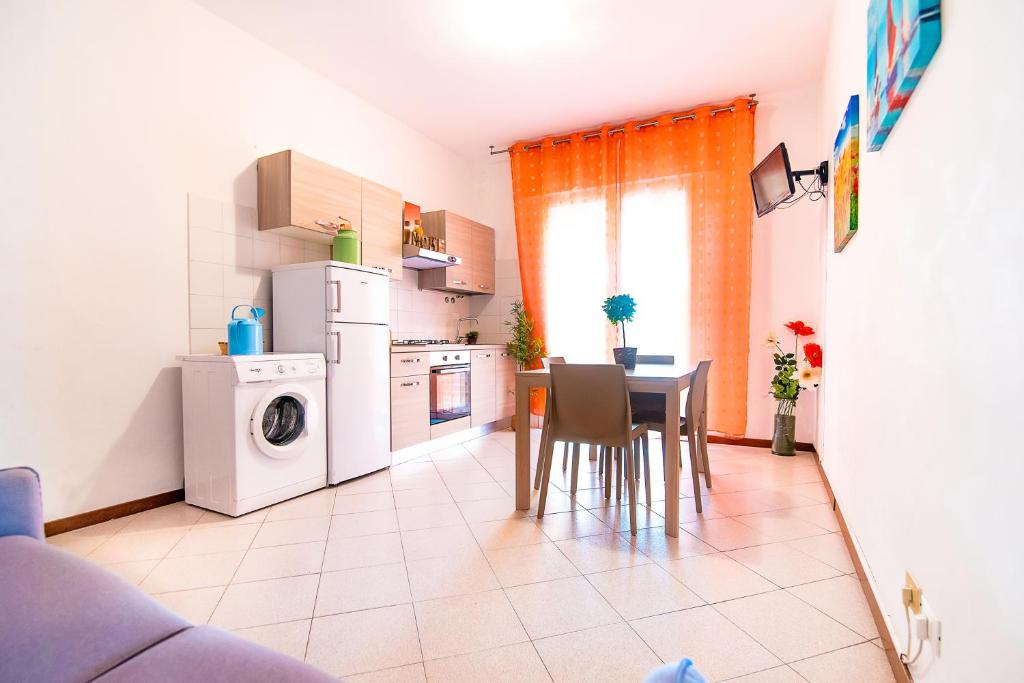 uma cozinha com uma mesa, um frigorífico e uma máquina de lavar roupa em Residence Comfort em Lido di Jesolo