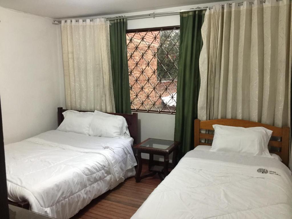 two beds in a small room with a window at Hotel Don Olivo in Bogotá