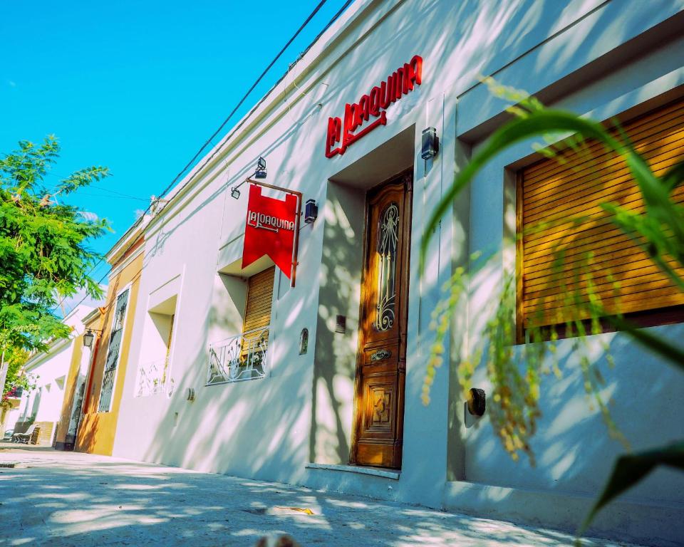 a white building with a red sign on the side of it at La Joaquina in Chascomús