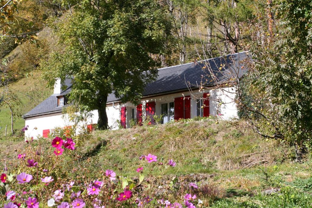een wit huis op een heuvel met bloemen bij Comfortable farm house Petit Barzun, in the Parc National Pyrenees in Barèges