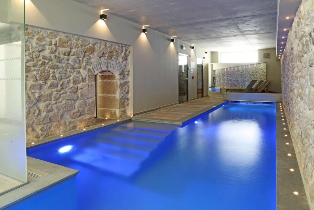 a blue pool in a room with a stone wall at Best Western Plus Hôtel La Joliette in Marseille