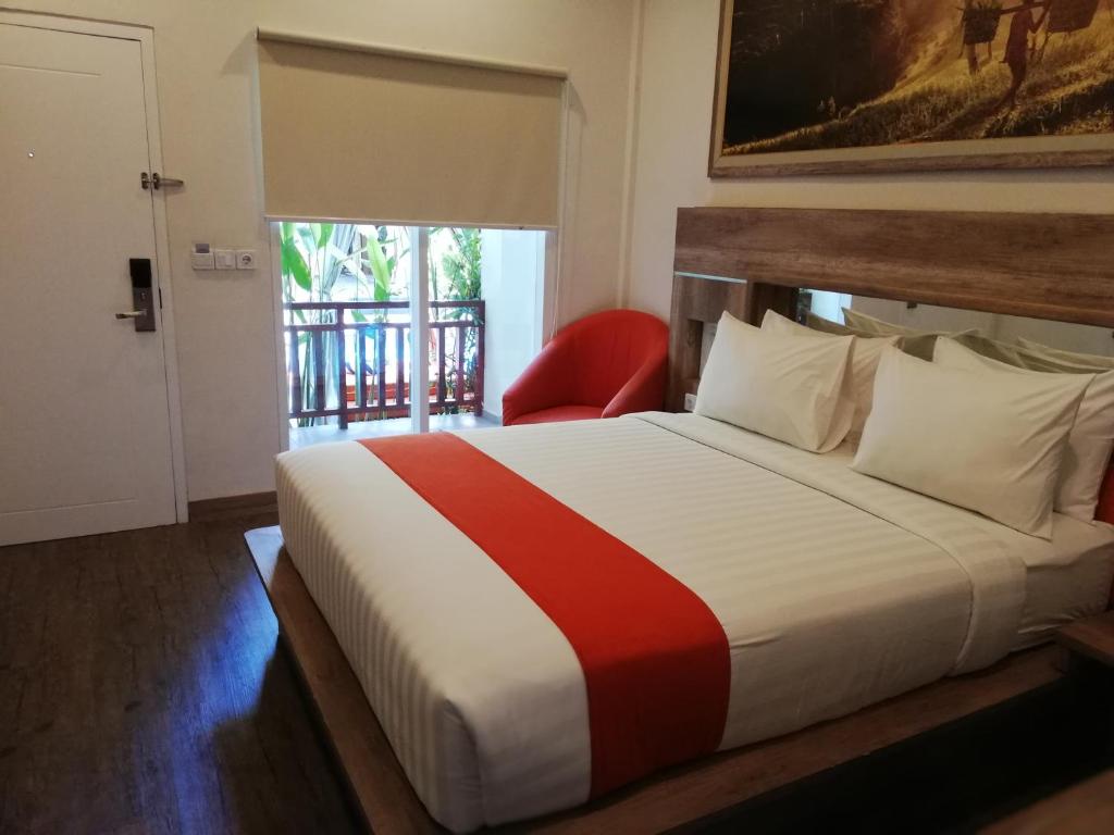 een slaapkamer met een groot bed met een rode stoel bij The Nyaman Bali in Kuta